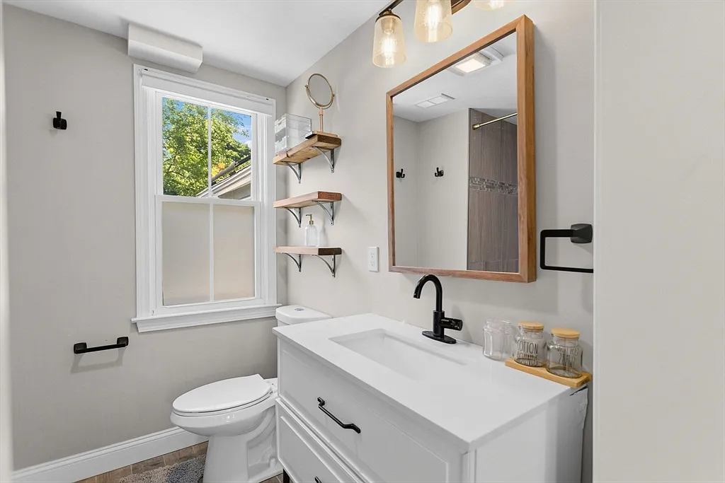 Bright bathroom with a white vanity, wood-framed mirror, and black fixtures