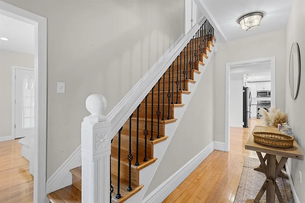 Finished hallway with a wood staircase, white trim, and black metal balusters