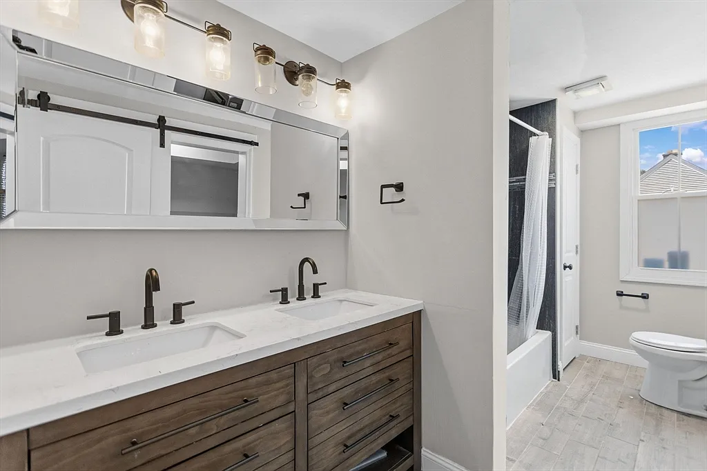 Double bathroom vanity with wood cabinets, white counter, and black faucets
