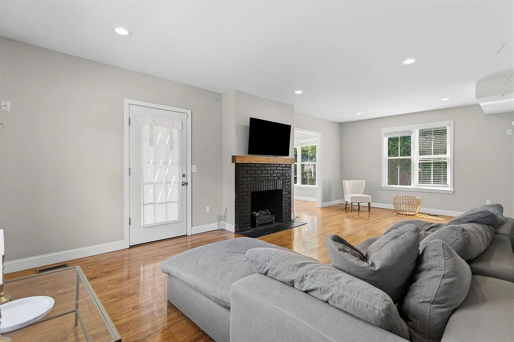 Bright living room with wood flooring, gray seating, and a black fireplace