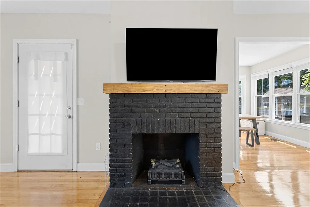 Black brick fireplace with a wood mantel between two doorways