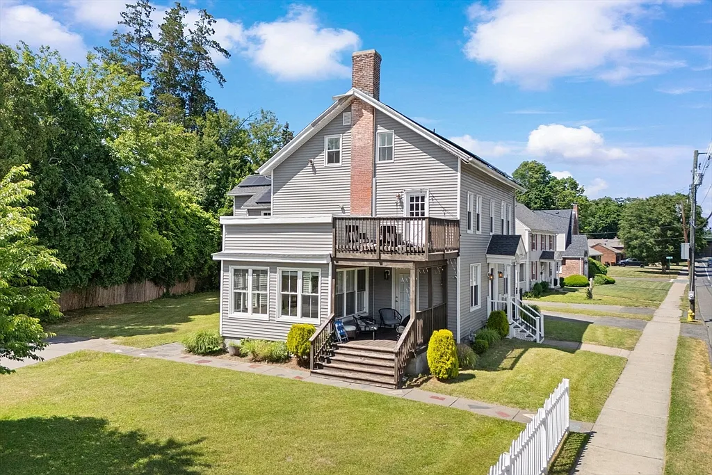 Rear and side exterior of a gray two-story house with a raised deck