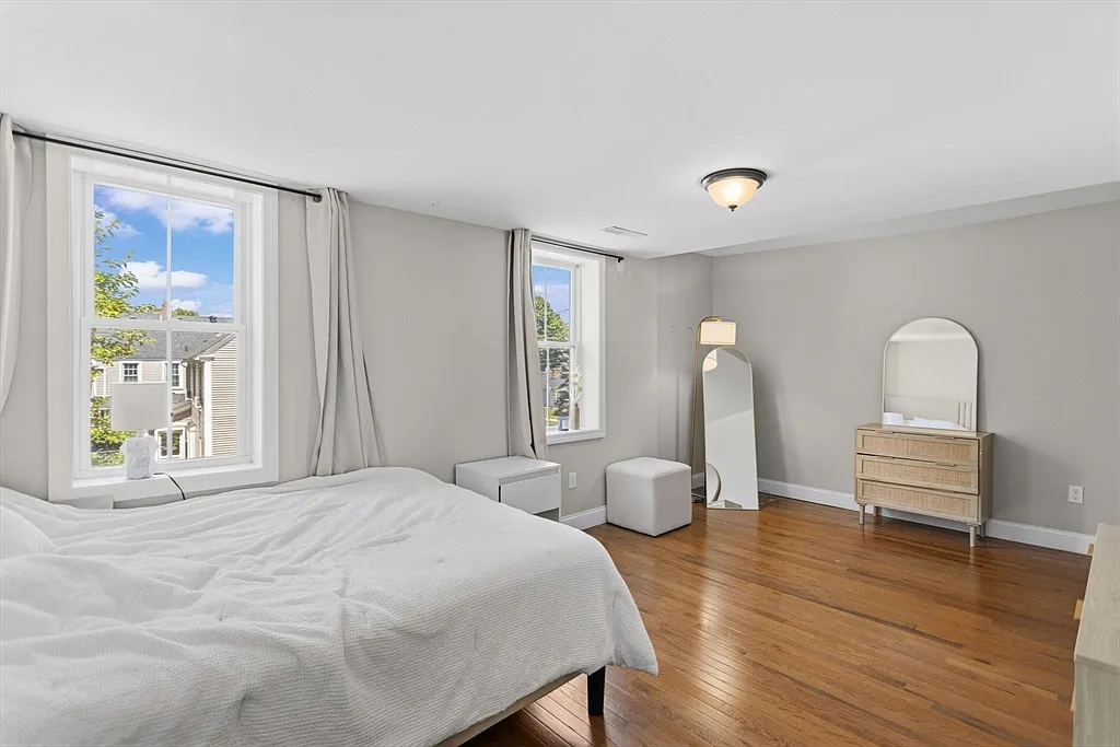 Bright bedroom with wood flooring, gray walls, and two windows